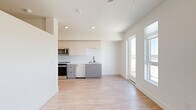 Located at 251 6th St. in downtown Sacramento, CA, this thoughtfully designed one-bedroom, one-bathroom residence offers a clean, modern aesthetic throughout its efficiently utilized single-floor layout. The open-concept living, dining, and kitchen area serves as the heart of the unit, featuring light-toned luxury vinyl plank flooring, recessed lighting, and large windows that flood the space with natural light. The kitchen is outfitted with two-tone cabinetry in white and gray, a white subway tile backsplash, stainless steel appliances including a range, microwave, and dishwasher, and a sleek sink with a matte black pull-down faucet. A glass door off the kitchen area opens to an outdoor space with views of the Sacramento skyline. The hallway connects all rooms efficiently and includes a dedicated laundry closet. The bedroom features plush carpeting, a ceiling fan, and a tray ceiling detail that adds architectural interest. The bathroom is finished with wood-look tile flooring, a modern floating vanity with white countertop, built-in open shelving, and a walk-in shower enclosed by a sliding frameless glass door with matte black hardware. The unit's crisp white walls and minimalist design create a bright, contemporary ambiance throughout.
