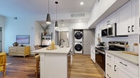 Located at Homestead in Fort Collins, Colorado, this single-story residence offers a thoughtfully designed open-concept layout with one bedroom, two full bathrooms, and a dedicated closet. Wood-look flooring flows throughout the main living areas, creating a warm and cohesive aesthetic.

The kitchen is a standout feature, showcasing white shaker-style cabinetry with matte black hardware, a white subway tile backsplash, stainless steel appliances including a range, microwave, and dishwasher, and a central island with a quartz countertop and undermount sink. Sleek pendant lighting accents the island and adds a modern touch.

The kitchen opens seamlessly into the living room, which is filled with natural light from large windows and a glass exterior door. The space offers a comfortable, inviting atmosphere well-suited for relaxing or entertaining.

The bedroom features plush carpeting and sheer window treatments that allow abundant natural light. Both bathrooms are finished with white cabinetry, quartz countertops, matte black fixtures, tub-shower combinations with white tile surrounds, and wood-look flooring, presenting a clean and contemporary look throughout. The overall design balances modern style with functional, everyday livability.