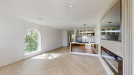 Located at 4326 Mission Rd in Kansas City, Kansas, this thoughtfully renovated single-floor space showcases a refined blend of modern design and high-end finishes. The open-concept living and kitchen area is anchored by striking light oak herringbone flooring that runs throughout, creating a warm yet sophisticated aesthetic.

The kitchen is a standout feature, equipped with a waterfall-edge quartz island, glass-front cabinetry with brushed gold hardware, a hexagonal tile backsplash, and stainless steel appliances including a built-in microwave. A sculptural double-ring pendant light adds an artistic focal point above the island, while open gold wall shelves offer both style and function. A dedicated entertainment wall with fluted wood paneling provides an elegant backdrop for media display.

Natural light fills the living area through generous windows, including a charming arched window that frames lush greenery outside. Recessed lighting throughout ensures a bright and airy atmosphere.

The bathroom continues the luxury theme with floor-to-ceiling marble-look tile, a frameless glass walk-in shower, hexagonal mosaic floor tiles, and gold fixtures including a rainfall showerhead and oversized pull handle. An in-unit laundry area is neatly integrated nearby. This space delivers a polished, move-in-ready experience with premium details at every turn.