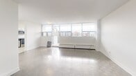 Located at Fowler Drive in Mississauga, this one-bedroom, one-bathroom unit offers a well-organized layout across a single floor. The bright white walls and light-toned parquet flooring create a clean, modern aesthetic throughout the space.

The living room is a standout, featuring a wide band of floor-to-ceiling windows that flood the room with natural light and frame panoramic views of the surrounding Mississauga cityscape. Baseboard heating runs beneath the windows, and the open feel of the room provides excellent versatility for furniture arrangement.

The kitchen is thoughtfully appointed with stainless steel appliances, including a range and over-the-range microwave, complemented by white cabinetry and a herringbone-patterned tile backsplash. Light-toned floor tiles and a window overlooking the city make the kitchen feel airy and functional.

The bedroom is a comfortable, well-proportioned room with the same consistent white walls and parquet flooring, offering a calm and quiet retreat.

The bathroom features crisp white subway tile surrounding the soaker tub and shower, paired with large-format stone-look floor tiles, a floating vanity with a white countertop, and a large mirror — a clean, contemporary finish throughout.

Overall, the unit offers a bright, minimalist atmosphere with consistent finishes and sweeping urban views.