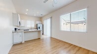 This well-appointed single-floor home offers a clean, modern aesthetic defined by light tones, consistent hardwood-style flooring, and an abundance of natural light throughout. The open-concept living and kitchen area forms the heart of the home, where the two spaces flow seamlessly into one another. A ceiling fan overhead and large windows fitted with blinds keep the living area comfortable and bright, while a sliding glass door provides access to the outdoors.

The kitchen is thoughtfully designed with crisp white shaker-style cabinetry, stone-look granite countertops, and a full suite of stainless steel appliances including a refrigerator with ice and water dispenser, an electric range, an over-the-range microwave, a dishwasher, and a double-basin sink with a brushed nickel faucet. A peninsula counter connects the kitchen to the living space, ideal for casual dining or entertaining.

The bedroom features vaulted ceilings that contribute to a spacious feel, along with dual closets offering generous built-in storage with hanging rods. The bathroom continues the home's consistent design language with white cabinetry, granite countertops, and hardwood-style flooring, complemented by a high window that brings in natural light while maintaining privacy. Throughout, the home presents a cohesive, neutral palette that is both inviting and functional.