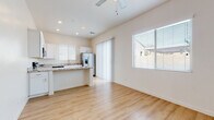 This well-appointed single-floor home offers a clean, modern aesthetic defined by light tones, consistent hardwood-style flooring, and an abundance of natural light throughout. The open-concept living and kitchen area forms the heart of the home, where the two spaces flow seamlessly into one another. A ceiling fan overhead and large windows fitted with blinds keep the living area comfortable and bright, while a sliding glass door provides access to the outdoors.

The kitchen is thoughtfully designed with crisp white shaker-style cabinetry, stone-look granite countertops, and a full suite of stainless steel appliances including a refrigerator with ice and water dispenser, an electric range, an over-the-range microwave, a dishwasher, and a double-basin sink with a brushed nickel faucet. A peninsula counter connects the kitchen to the living space, ideal for casual dining or entertaining.

The bedroom features vaulted ceilings that contribute to a spacious feel, along with dual closets offering generous built-in storage with hanging rods. The bathroom continues the home's consistent design language with white cabinetry, granite countertops, and hardwood-style flooring, complemented by a high window that brings in natural light while maintaining privacy. Throughout, the home presents a cohesive, neutral palette that is both inviting and functional.
