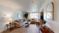 Located at 100 Park Plaza Dr in Pittsburgh, PA, this one-bedroom, one-bathroom unit offers a well-organized single-floor layout across a comfortable living footprint. The living room is carpeted and open in feel, featuring neutral walls, recessed lighting, and enough space for a full seating arrangement and dining area. Large windows allow natural light to filter through, enhancing the room's bright and airy ambiance.

The kitchen is efficiently designed with warm wood cabinetry, dark granite-style countertops, and tile flooring. It is fully equipped with black appliances including a refrigerator, dishwasher, microwave, and electric range, along with ample cabinet and counter space for everyday use.

The bedroom is a well-proportioned retreat featuring plush carpeting, a ceiling fan with light fixture, and a window with curtains that invite natural light while maintaining privacy. A built-in closet with bifold doors provides convenient storage, complemented by additional dresser space.

The bathroom is clean and straightforward, featuring a combined tub and shower with a curtain, tiled flooring, and a simple, functional layout. A connecting hallway ties all rooms together in a logical flow, making the overall layout easy to navigate. This unit offers a practical and comfortable living environment suitable for individuals or couples.