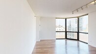 Located in Chicago's vibrant Gold Coast neighborhood, this two-bedroom, one-bathroom residence offers a well-designed layout with an open living and dining area that flows seamlessly into the kitchen. The living room is a standout space, featuring floor-to-ceiling wraparound windows that flood the room with natural light and frame sweeping views of the Chicago skyline. Light-toned hardwood flooring runs throughout, complemented by track lighting and clean white walls that give the space a bright, contemporary feel. The kitchen is outfitted with dark lower cabinetry contrasted by white upper cabinets and light countertops, along with stainless steel appliances including a refrigerator, dishwasher, and range. Both bedrooms continue the hardwood flooring and enjoy generous natural light, with the primary bedroom offering a spacious footprint and its own access to the panoramic city views through large corner windows. Two closets provide practical storage solutions throughout the unit. The bathroom features classic black-and-white mosaic tile flooring, a dark vanity with a white countertop, and a tiled shower-tub combination. The overall ambiance is clean, modern, and airy, ideal for urban living in one of Chicago's most sought-after neighborhoods.
