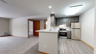 Located at 806 Riverwalk Dr in Waukesha, Wisconsin, this well-appointed one-bedroom, one-bathroom unit offers a functional and comfortable single-floor layout. The open-concept kitchen flows seamlessly into the combined dining and living area, creating an inviting and versatile space. The kitchen is outfitted with dark gray cabinetry, a marble-look countertop peninsula with a built-in sink, stainless steel appliances including a gas range and refrigerator, and durable light wood-tone vinyl flooring. A skylight and recessed lighting keep the area bright and welcoming. The living room is carpeted and features a sliding glass door that opens to a private balcony, filling the space with natural light and outdoor views. The generously sized bedroom is carpeted as well, with a window for additional natural light and warm wood-trimmed doors. It includes access to a dedicated walk-in closet outfitted with wire shelving and organizers, plus a secondary closet nearby. The bathroom is clean and modern, featuring a tub-shower combo, a dark-vanity with a white countertop, and wood-tone vinyl flooring consistent with the rest of the unit. A utility area with an electrical panel and additional storage access completes this well-organized home.