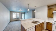 Located at 6930 W Silverado St in Rathdrum, Idaho, this single-floor, 2-bedroom, 3-bathroom residence offers a practical and comfortable layout. The open-concept kitchen and living area serves as the heart of the home, where warm honey-toned cabinetry, light countertops, and light wood-style flooring create an inviting atmosphere. The kitchen is well-equipped with ample cabinet storage, a double sink, an electric range with overhead ventilation, and full-size appliances including a refrigerator and microwave. Pendant lighting above the breakfast bar adds a welcoming touch, while the bar itself provides a natural divide between the kitchen and the carpeted living room. The living room receives natural light through large windows fitted with vertical blinds and features a private entry door. Both bedrooms are carpeted and offer generous sliding-door closets with contemporary wood-grain finishes. The spacious primary bedroom benefits from a large window that invites natural light. Three bathrooms provide convenience, each featuring tile flooring, vanity storage, and clean, neutral finishes. A connecting hallway ties the layout together efficiently. The textured ceilings and neutral wall tones throughout give the space a cohesive, move-in-ready feel.