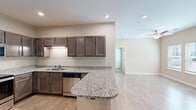 Located at 1910 E First St in Gulf Shores, Alabama, this 2-bedroom, 2-bathroom single-floor residence offers a well-designed layout that maximizes functionality and comfort. The open-concept kitchen flows seamlessly into the living area, creating a connected and airy feel. The kitchen is equipped with rich dark-toned cabinetry, granite countertops, stainless steel appliances including a refrigerator, range, microwave, and dishwasher, along with a peninsula that provides additional prep and casual dining space. Light wood-look flooring runs throughout the main living areas, adding warmth and continuity. The living room benefits from natural light through windows and is finished with a ceiling fan overhead. Both bedrooms feature plush carpeting and ceiling fixtures, with the second bedroom offering dual windows that invite natural light and outdoor views. The two bathrooms are appointed with granite-topped dark wood vanities and wood-look tile flooring; one includes a walk-in shower and the other a full soaking tub. A dedicated in-unit laundry area with wire shelving adds everyday convenience. A closet provides additional storage, rounding out this thoughtfully arranged and move-in-ready residence.