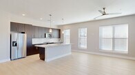 Located at 1110 Metropolitan Ave in Summerville, SC, this well-appointed 2-bedroom, 2-bathroom home offers a thoughtfully designed single-level layout with modern finishes throughout. The open-concept kitchen and living area serves as the heart of the home, anchored by a large granite-topped island with pendant lighting and a built-in sink. Rich dark cabinetry reaches to the ceiling, complemented by a white subway tile backsplash and stainless steel appliances. The living area benefits from multiple windows that flood the space with natural light, while a ceiling fan adds comfort. Light wood-style flooring runs consistently throughout, enhancing the clean, contemporary aesthetic. The generously sized primary bedroom features multiple windows with outdoor views and ample room for furnishings. The second bedroom includes a ceiling fan, natural light, and direct access to the outdoors. Four closets provide exceptional storage across the home. The primary bathroom offers a glass-enclosed walk-in shower with full tile surround, a dark wood vanity with granite countertop, and framed mirror. The second bathroom features a sliding glass shower-tub combination with matching granite vanity finishes. Neutral warm-toned walls and crisp white trim tie each space together with a cohesive, move-in-ready appeal.