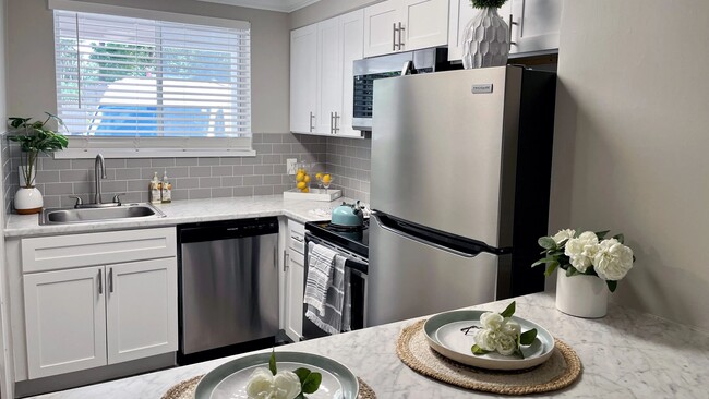 Indulge in the allure of elevated modern kitchen offerings adorned with luxurious white marble-inspired countertops, a sophisticated grey backsplash, and sleek white shaker cabinets. - Lakewood Village