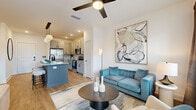 This thoughtfully designed 1-bedroom, 1-bathroom residence offers a cohesive open-concept layout that maximizes every square foot. Light wood-look flooring flows throughout the main living areas, anchoring a bright and modern aesthetic defined by crisp white walls and recessed lighting.

The kitchen is a standout feature, showcasing gray shaker-style cabinetry, granite countertops, a full suite of stainless steel appliances, and a tile backsplash. A central island with a contrasting slate-blue base provides seating for multiple bar stools and is illuminated by a trio of globe pendant lights, making it a natural hub for dining and entertaining. The kitchen connects seamlessly to the living room, which benefits from large windows and a patio door that invite natural light and outdoor views. A ceiling fan adds to the comfort of the space.

The bedroom is a serene retreat featuring plush carpet, a ceiling fan, and a window with natural light. A dedicated closet provides practical storage. The bathroom is finished with granite countertops, gray cabinetry with matte black hardware, wood-look flooring, and a large wall mirror above the vanity. Every room reflects a consistent, contemporary design language with careful attention to detail.
