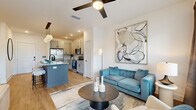 This thoughtfully designed 1-bedroom, 1-bathroom residence offers a cohesive open-concept layout that maximizes every square foot. Light wood-look flooring flows throughout the main living areas, anchoring a bright and modern aesthetic defined by crisp white walls and recessed lighting.

The kitchen is a standout feature, showcasing gray shaker-style cabinetry, granite countertops, a full suite of stainless steel appliances, and a tile backsplash. A central island with a contrasting slate-blue base provides seating for multiple bar stools and is illuminated by a trio of globe pendant lights, making it a natural hub for dining and entertaining. The kitchen connects seamlessly to the living room, which benefits from large windows and a patio door that invite natural light and outdoor views. A ceiling fan adds to the comfort of the space.

The bedroom is a serene retreat featuring plush carpet, a ceiling fan, and a window with natural light. A dedicated closet provides practical storage. The bathroom is finished with granite countertops, gray cabinetry with matte black hardware, wood-look flooring, and a large wall mirror above the vanity. Every room reflects a consistent, contemporary design language with careful attention to detail.