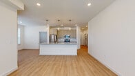 This well-appointed 2-bedroom, 2-bathroom residence offers a clean, modern aesthetic across a single floor of comfortable living space. The open-concept kitchen and living area serves as the heart of the home, featuring a central island with granite countertops, an undermount sink, and stylish pendant lighting overhead. Gray shaker-style cabinetry, a subway tile backsplash, and a full suite of stainless steel appliances complete the kitchen. Light-toned luxury vinyl plank flooring flows seamlessly throughout the entire residence, enhancing the bright, airy atmosphere created by recessed lighting and generous natural light. A central hallway connects the living areas to both bedrooms, each featuring ceiling fans and dedicated walk-in closets with built-in shelving. The primary bedroom includes a walk-in closet and an en-suite bathroom with a dual-sink vanity, granite countertops, and a tiled shower. The second bathroom offers a tub-shower combination with marble-style tile surround and matching granite vanity. Additional spaces include two closets, a utility room, and a hallway, providing ample storage throughout. The residence presents a cohesive, contemporary design with neutral tones and quality finishes at every turn.