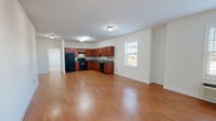 Located at 255 East Grand Avenue in Rahway, New Jersey, this two-bedroom, two-bathroom residence offers a comfortable and functional single-floor layout. The open-plan living and dining area is a welcoming centerpiece, featuring warm hardwood-style flooring and bright, neutral walls that create an airy, versatile space ideal for both relaxing and entertaining.

The kitchen is thoughtfully designed with rich cherry wood cabinetry extending to the upper walls, dark granite-style countertops, a mosaic tile backsplash, and black appliances including a range, refrigerator, and dishwasher — all set atop matching hardwood-style flooring that flows seamlessly from the living area.

Both bedrooms are carpeted for comfort and feature generous closet storage, with the primary bedroom offering a particularly spacious feel and its own dedicated bathroom. One bathroom features a walk-in shower with a glass-panel door and a cherry wood vanity, while the second bath includes a full soaking tub and shower combination, also finished with light tile flooring and a matching vanity. A hallway connects the rooms efficiently, and five closets distributed throughout the residence provide exceptional storage capacity.