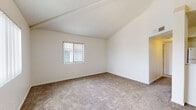 Located at 6200 S Campbell Ave in Tucson, Arizona, this single-story residence offers a clean, straightforward layout designed for comfortable everyday living. The interior is finished with neutral, light-toned walls throughout, creating a bright and open atmosphere across all rooms.

The living area features plush wall-to-wall carpeting and vaulted ceilings with a textured finish, adding a sense of height and airiness to the space. Vertical blind-covered windows allow natural light to filter in while maintaining privacy. A sliding glass door provides additional light and outdoor access.

The kitchen is equipped with warm-toned wood cabinetry, dark granite-style countertops, and wood-look vinyl flooring. Appliances include a refrigerator, range, and dishwasher, along with a sink set within the countertop — offering a fully functional cooking space.

The bedrooms are carpeted and well-proportioned, each featuring windows that bring in natural light and views of the surrounding neighborhood. At least one bedroom includes a walk-in closet with built-in shelving, providing ample storage. Additional closet space is also present in other rooms.

The entryway transitions from wood-look vinyl flooring into the carpeted main living areas, creating a clear and practical delineation between spaces. Overall, the residence presents a tidy, move-in-ready interior with a consistent and cohesive design throughout.