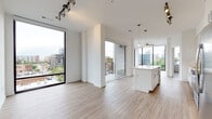 Located at 682 N Grant St in Denver's Capitol Hill neighborhood, this contemporary single-floor residence showcases a clean, modern design defined by an open-concept layout and an abundance of natural light. Light-toned hardwood-style flooring runs throughout, creating a cohesive and airy aesthetic across every room.

The living and dining area is anchored by expansive floor-to-ceiling windows and a sliding glass door that opens to a private balcony, offering elevated views of the Denver skyline and surrounding urban landscape. Track lighting accents the space, complementing the generous natural light.

The kitchen is well-appointed with white flat-front cabinetry extending to the ceiling, a mosaic tile backsplash, stainless steel appliances including a refrigerator, range, and built-in microwave, and a large central island with a quartz countertop that provides additional workspace and seating. Pendant and track lighting illuminate the area effectively.

The bedrooms are bright and generously proportioned, each featuring ceiling fans and large windows with city views. The primary bathroom is notably spacious, featuring a dual-sink vanity with white quartz countertops, a glass-enclosed shower, wood-look flooring, and direct access to a walk-in closet with built-in shelving.