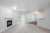This single-floor residence offers a thoughtfully designed layout that balances comfort and functionality throughout its living spaces. The spacious living room serves as a central gathering area, highlighted by a built-in fireplace with a clean white mantel and sliding glass doors fitted with vertical blinds that provide access to an outdoor patio. Neutral-toned carpet flows throughout the living and bedroom areas, lending a warm and cohesive feel to the space.

Adjacent to the living room, the dining area features wood-look flooring, a chandelier overhead, a bright window framing greenery outside, and direct access to a second patio door. The kitchen is efficiently designed with white cabinetry, a subway tile backsplash, dark countertops, stainless steel appliances including a range and refrigerator, and a peninsula that opens toward the dining area.

The bedrooms are carpeted and well-lit by natural light from windows overlooking outdoor greenery, with baseboard heating providing comfort. Bathrooms include a full bath with a soaking tub and tile flooring, and a second bath featuring a glass-enclosed shower and wood-look flooring. Throughout the residence, neutral walls and clean finishes create a bright, move-in-ready atmosphere.