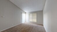 This well-organized 1-bedroom, 1-bathroom unit is thoughtfully laid out across a single floor, offering an efficient and functional living space. The living room is a standout area, featuring soaring vaulted ceilings that lend an open, airy feel well beyond its physical footprint. Soft carpeting covers the floor, and a large window with blinds alongside a sliding glass door floods the room with natural light. Neutral gray walls and a textured ceiling complete the welcoming atmosphere.

The kitchen is positioned adjacent to the living area and features white cabinetry, dark speckled countertops, wood-look flooring, and a full-size refrigerator, providing a practical cooking space.

The bedroom is a comfortable, well-proportioned room with its own window for natural light, plush carpeting, and a textured ceiling. Three closets throughout the unit offer generous storage options.

The bathroom is clean and straightforward, featuring a full tub-shower combination with white tile surround, a toilet, and wood-look flooring, complemented by cabinetry with dark countertops just outside. Overall, the unit presents a practical and comfortable living environment with consistent finishes throughout.