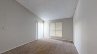 This well-organized 1-bedroom, 1-bathroom unit is thoughtfully laid out across a single floor, offering an efficient and functional living space. The living room is a standout area, featuring soaring vaulted ceilings that lend an open, airy feel well beyond its physical footprint. Soft carpeting covers the floor, and a large window with blinds alongside a sliding glass door floods the room with natural light. Neutral gray walls and a textured ceiling complete the welcoming atmosphere.

The kitchen is positioned adjacent to the living area and features white cabinetry, dark speckled countertops, wood-look flooring, and a full-size refrigerator, providing a practical cooking space.

The bedroom is a comfortable, well-proportioned room with its own window for natural light, plush carpeting, and a textured ceiling. Three closets throughout the unit offer generous storage options.

The bathroom is clean and straightforward, featuring a full tub-shower combination with white tile surround, a toilet, and wood-look flooring, complemented by cabinetry with dark countertops just outside. Overall, the unit presents a practical and comfortable living environment with consistent finishes throughout.