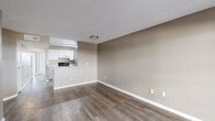 This single-floor residence offers a clean, modern aesthetic throughout, with a neutral warm-beige color palette and white trim that lend a cohesive and inviting feel. The open living and dining area is finished with durable wood-look plank flooring and features a textured ceiling, recessed lighting, and direct access to a private patio through a sliding glass door, allowing natural light to flow in. A pass-through connects the living area to the kitchen, which is well-equipped with stainless steel appliances including a range, dishwasher, and refrigerator, complemented by white cabinetry with brushed nickel hardware and granite-look countertops. A second room with wood-look flooring and its own sliding glass door provides additional flexible living space with outdoor access. The carpeted bedrooms offer a comfortable retreat, each finished with the same neutral tones; one bedroom features a window with exterior views and access to a sliding-door closet with a full hanging rod. The bathrooms are neatly appointed with white vanities, updated fixtures, and wood-look flooring; one includes a tub-shower combination. Throughout, the consistent finishes and thoughtful layout make this a functional and comfortable living space.
