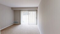 Located at 955 Richwood Rd in Bel Air, Maryland, this one-bedroom, one-bathroom unit offers a well-organized single-floor layout designed for comfortable everyday living. The living room is a standout feature, highlighted by a full-width sliding glass door dressed with vertical blinds that allow abundant natural light and provide outdoor access. Neutral-toned carpet, soft gray walls, and clean white trim create a cohesive, understated aesthetic throughout the carpeted areas. The kitchen is equipped with a black electric range, granite-look countertops, white cabinetry, and a ventilation hood. Light wood-style flooring and a bright window make this space feel open and functional. A dedicated dining area adjoins the kitchen, providing additional utility. The spacious bedroom offers generous square footage and features two separate doorways — one leading to a full bathroom and another to a walk-in closet equipped with dual wire shelving racks for ample storage. A second closet is also accessible near the living area. The full bathroom includes a tub-shower combination with a curtain rod, a toilet, and wood-style flooring, maintaining the home's consistent neutral palette. The overall ambiance is clean, bright, and move-in ready.