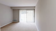 Located at 955 Richwood Rd in Bel Air, Maryland, this one-bedroom, one-bathroom unit offers a well-organized single-floor layout designed for comfortable everyday living. The living room is a standout feature, highlighted by a full-width sliding glass door dressed with vertical blinds that allow abundant natural light and provide outdoor access. Neutral-toned carpet, soft gray walls, and clean white trim create a cohesive, understated aesthetic throughout the carpeted areas. The kitchen is equipped with a black electric range, granite-look countertops, white cabinetry, and a ventilation hood. Light wood-style flooring and a bright window make this space feel open and functional. A dedicated dining area adjoins the kitchen, providing additional utility. The spacious bedroom offers generous square footage and features two separate doorways — one leading to a full bathroom and another to a walk-in closet equipped with dual wire shelving racks for ample storage. A second closet is also accessible near the living area. The full bathroom includes a tub-shower combination with a curtain rod, a toilet, and wood-style flooring, maintaining the home's consistent neutral palette. The overall ambiance is clean, bright, and move-in ready.