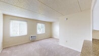 Located at 7517 North 40th Street in Tampa, Florida, this efficiently designed studio unit offers a well-organized single-floor layout that maximizes every square foot of available space. The main living area features soft neutral carpeting, textured ceilings, and concrete block walls finished in a warm cream tone, lending the space a clean and understated character. Two windows with blinds allow natural light to fill the room, while a wall-mounted air conditioning unit provides climate control. Adjacent to the living area, the galley-style kitchen is thoughtfully appointed with white cabinetry, granite-look countertops, a white electric range, overhead ventilation, and hardwood-style flooring that adds warmth and contrast. The bathroom continues the clean aesthetic with a full tub and shower combination accented by chrome grab bars and a shower rod, complemented by a vanity with granite-look countertops, a white sink, and hardwood-style flooring. A dedicated closet provides additional storage. Hallways connect the various areas of the unit, contributing to a logical and functional flow throughout. This unit offers a straightforward, practical living space in the established Seminole Heights neighborhood of Tampa.