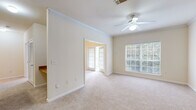 Located at 100 Stonecrest Blvd in Stonecrest, Georgia, this single-floor home offers a thoughtfully designed layout with comfortable living spaces throughout. The living area features soft carpeting, crown molding, and a ceiling fan with light fixture, complemented by large windows that invite abundant natural light and views of surrounding greenery. An elegant arched doorway connects the living space to a hallway, adding a classic architectural touch. Adjacent to the main living area, a secondary room with French doors provides flexible use as a sitting room, office, or dining space.

The kitchen is well-appointed with warm wood cabinetry, tile backsplash, ample counter space, and a central island that provides additional workspace and storage. White appliances, including a range, dishwasher, and refrigerator, complete the functional setup. The open sightlines between the kitchen and living area create a cohesive and practical flow.

Bedrooms are generously sized with plush carpeting and large windows overlooking lush outdoor scenery. The primary bedroom includes a spacious walk-in closet outfitted with wire shelving for organized storage. The bathroom features a tiled tub-shower combination with a decorative dark tile accent border. A dedicated laundry room accommodates a full-size washer and dryer side by side, adding everyday convenience to this well-rounded home.