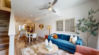 Located at 6525 Ed Bluestein Boulevard in Austin, TX, this two-story, 2-bedroom, 2-bathroom home offers a well-designed layout spread across two floors. The main level hosts the open-concept living, dining, and kitchen area, bathed in natural light from large windows. The living room features wood-look flooring, a ceiling fan, and direct access to a private concrete patio framed by stone exterior walls and open green space views. The kitchen is outfitted with white shaker cabinetry, granite countertops, stainless steel appliances, a subway tile backsplash, and a peninsula with pendant lighting and bar seating — ideal for both cooking and entertaining. The adjacent dining area provides a dedicated space for meals. Both bathrooms include granite-topped vanities, wood-look flooring, and glass-enclosed walk-in showers with marble-style tile surround. The primary bedroom offers generous proportions with a ceiling fan, natural light, and outdoor access. The second bedroom is bright and airy, with dual windows and ample space. A staircase connects the two levels, with hallways on each floor providing functional flow throughout this clean, contemporary Austin home.