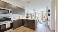 Located at 3842 W Northwest Highway in Dallas, TX, this one-bedroom, one-bathroom residence offers a thoughtfully designed layout across a single floor. The open-concept kitchen and living area serves as the heart of the unit, where rich dark-toned cabinetry, stainless steel appliances — including a side-by-side refrigerator, range, and built-in microwave — and crisp white countertops create a sleek, modern kitchen. Pendant lighting over the peninsula adds both function and style, while light wood-look flooring flows seamlessly throughout the main living areas. The living room is bright and welcoming, featuring a ceiling fan, recessed lighting, and French doors that open to a private balcony with outdoor views, filling the space with natural light. The bedroom is a comfortable retreat with large windows fitted with blinds, plush carpeting, and two closets for ample storage. The bathroom features dark cabinetry with a dual-sink vanity and a large mirror, maintaining the modern aesthetic found throughout the unit. Additional conveniences include a dedicated laundry area and utility room. The overall ambiance is contemporary and cohesive, with clean lines and neutral tones throughout.