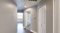 Located on the 18th floor at 410 W 7th Street in downtown Fort Worth, Texas, this one-bedroom, one-bathroom unit offers a well-organized layout across a single floor. Hardwood-style flooring runs throughout the space, complemented by neutral-toned walls and clean white baseboards that create a consistent, modern aesthetic.

The galley-style kitchen is efficiently designed with white shaker cabinetry, a subway tile backsplash, taupe countertops, a single-basin sink, and stainless steel appliances including a refrigerator and dishwasher. Recessed lighting keeps the kitchen bright and functional.

The living area is open and airy, with ample wall space and direct access to the kitchen. The bedroom features multiple large windows that flood the room with natural light and frame elevated views of the Fort Worth skyline and surrounding cityscape. A dedicated closet provides practical storage.

The bathroom includes a tiled tub-shower combination, a toilet, and a vanity with overhead lighting, finished in a clean, all-white palette. The hallway connecting the rooms includes additional storage access and ceiling ventilation. Throughout the unit, the design prioritizes clean lines, neutral finishes, and functional use of space in a high-rise downtown setting.