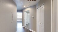 Located on the 18th floor at 410 W 7th Street in downtown Fort Worth, Texas, this one-bedroom, one-bathroom unit offers a well-organized layout across a single floor. Hardwood-style flooring runs throughout the space, complemented by neutral-toned walls and clean white baseboards that create a consistent, modern aesthetic.

The galley-style kitchen is efficiently designed with white shaker cabinetry, a subway tile backsplash, taupe countertops, a single-basin sink, and stainless steel appliances including a refrigerator and dishwasher. Recessed lighting keeps the kitchen bright and functional.

The living area is open and airy, with ample wall space and direct access to the kitchen. The bedroom features multiple large windows that flood the room with natural light and frame elevated views of the Fort Worth skyline and surrounding cityscape. A dedicated closet provides practical storage.

The bathroom includes a tiled tub-shower combination, a toilet, and a vanity with overhead lighting, finished in a clean, all-white palette. The hallway connecting the rooms includes additional storage access and ceiling ventilation. Throughout the unit, the design prioritizes clean lines, neutral finishes, and functional use of space in a high-rise downtown setting.