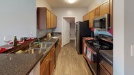 Located at 1005 W Trade St in Charlotte, NC, this single-floor residential unit offers a functional and comfortable layout throughout. The galley-style kitchen is equipped with stainless steel appliances, including a refrigerator, electric range, and microwave, complemented by warm wood cabinetry, dark granite-style countertops, a double stainless steel sink, and wood-look flooring. A walk-in closet is conveniently accessible directly from the kitchen area. The living room is carpeted and features a ceiling fan, vertical blinds, and sliding glass doors that open to a private balcony with outdoor views. The bedrooms are carpeted and well-lit by natural light through large windows with outdoor views. One bedroom offers an adjacent walk-in closet. A flexible room with carpet and a bright window serves well as a home office or additional bedroom. The primary bathroom features wood-look flooring, a rich wood vanity with dark countertops, and a tub/shower combination. The second full bathroom is similarly appointed with matching cabinetry, a tub/shower, and wood-look flooring. Soft, neutral gray tones throughout the unit create a cohesive and calming aesthetic.
