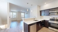 Located at 2281 East 89th St in Cleveland, OH, this well-appointed 2-bedroom, 2-bathroom home spans three floors, offering a thoughtfully designed layout with modern finishes throughout. The main living floor centers around an open-concept kitchen and living room, bathed in natural light from multiple windows. The kitchen is a standout feature, showcasing rich dark cabinetry, crisp white countertops, a peninsula with pendant lighting, and a full suite of stainless steel appliances including a refrigerator, range, microwave, and dishwasher. Light hardwood flooring flows seamlessly through the living and kitchen areas, enhancing the bright, airy atmosphere. Two staircases with striking dark treads and white risers connect the floors with clean, contemporary style. The upper floor hosts the bedrooms, both carpeted for comfort and filled with natural light. The spacious primary bedroom features a ceiling fan and ample room, while the second bedroom includes a wall-mounted AC unit and outdoor views. Two full bathrooms include tub-shower combinations with white tile surrounds and dark vanity cabinetry. Additional spaces include a laundry room, pantry, utility room, closets, and an entrance, rounding out this functional and modern home.
