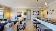 Located at 1951 Hunter Rd in San Marcos, TX, this well-appointed 2-bedroom, 2-bathroom residence offers a thoughtfully designed single-floor layout with a welcoming entrance and a hallway that connects all living areas. The open-concept great room seamlessly unites the living, dining, and kitchen spaces, all finished with polished stained concrete floors and crown molding throughout. Large windows flood the living area with natural light, while a sliding glass door in the dining area opens directly onto a private balcony with outdoor views. The kitchen is anchored by a dark-granite peninsula with bar stool seating, rich dark-wood cabinetry, stainless steel appliances, a pantry, and pendant lighting with additional track lighting overhead. Both bedrooms are generously sized, featuring neutral tones, crown molding, and ample closet space — five closets in total across the home. The bathrooms are finished with tiled tub-shower surrounds, dark wood vanities, and white countertops. A dedicated in-unit laundry area with built-in shelving adds everyday convenience. The layout also includes a hallway connecting the bedrooms, providing a clear separation between the living and private areas of the home.