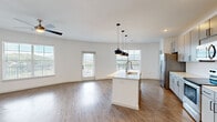 Located on Dublin Blvd in Colorado Springs, CO, this well-appointed 2-bedroom, 2-bathroom residence offers a thoughtfully designed single-floor layout with modern finishes throughout. The open-concept living and kitchen area serves as the heart of the home, anchored by a central island with a built-in sink and striking pendant lighting overhead. Grey cabinetry, stainless steel appliances, and a tile backsplash complete the kitchen, which flows seamlessly into the spacious living area. Warm hardwood-style flooring runs throughout the main living spaces, complemented by crisp white walls that enhance the sense of brightness. Large windows and a glass door flood the living room with natural light while offering scenic views of the surrounding Colorado landscape. A ceiling fan adds comfort to both the living area and bedrooms. The generously sized primary bedroom features plush carpeting, a ceiling fan, and direct access to a private en-suite bathroom, which includes a dual-sink vanity, marble-style shower, and an attached walk-in closet with built-in shelving and hanging rods. The second bedroom, also carpeted, is bright and well-proportioned with convenient closet access. This residence combines clean, contemporary design with functional living spaces in a desirable Colorado Springs location.