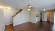 This two-story residence offers a well-organized layout across two floors, accommodating two bedrooms and two and a half bathrooms. The main level features durable wood-look flooring throughout the living and dining areas, which are connected by an open-concept design. A staircase leads to the upper level, and built-in shelving provides convenient storage near the living space. Ceiling fans are present throughout, contributing to overall comfort.

The kitchen is equipped with white cabinetry, dark granite-style countertops, black appliances including an electric range and refrigerator, and a pass-through counter that opens to the dining and living areas, promoting an open flow between spaces.

Upstairs, both bedrooms are carpeted and include ceiling fans. The primary bedroom is notably spacious and features multiple closets, including a walk-in, as well as a private en-suite bathroom. The second bedroom also offers generous proportions with natural light from a large window. A half bathroom is conveniently located on the main level, while full bathrooms with tub/shower combinations serve the upper floor. The textured ceilings are consistent throughout the home.