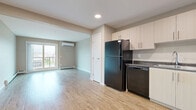 Located at 350 Bobolink Ridge in Ottawa's Barrhaven neighbourhood, this single-floor, 3-bedroom, 2-bathroom unit offers a practical and well-appointed layout. Throughout the space, light wood-style laminate flooring creates a cohesive and contemporary feel, complemented by neutral warm-beige walls and clean white trim.

The kitchen is efficiently designed with ample white cabinetry, dark granite-style countertops, and a full suite of black appliances including a refrigerator, electric range, dishwasher, and under-cabinet range hood. The living room is bright and open, featuring a wall-mounted ductless air conditioning unit, a baseboard heating system, and access to a private balcony through a glass door, allowing natural light to fill the space.

Each of the three bedrooms is well-proportioned with large windows fitted with horizontal blinds, offering views of the surrounding residential neighbourhood. The primary bedroom includes a built-in double closet with bi-fold doors. Both bathrooms are finished consistently, featuring full tub-shower combinations, toilets, and the same wood-style flooring found throughout the unit. The overall layout is functional and efficient, offering comfortable living within a modern residential community.