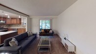 This single-floor residence offers a thoughtfully designed layout that balances comfort and functionality across its main living spaces. The living room is generously proportioned, featuring neutral white walls, carpeted flooring, and a vaulted ceiling detail that adds architectural interest. A large sliding glass door floods the space with natural light and provides outdoor views, while the open sightline to the kitchen enhances the sense of openness throughout.

The kitchen is a standout feature, equipped with rich warm-toned wood cabinetry, granite countertops, and a decorative mosaic tile backsplash. Stainless steel appliances, including a gas range, over-the-range microwave, French door refrigerator, and dishwasher, complete the well-appointed space. Tile flooring adds durability and a clean aesthetic.

The primary bedroom is spacious and carpeted, offering natural light through a window and notable closet space via dual bifold closets. The second bedroom is cozy and equally well-lit with its own window and neutral carpeting. Both bathrooms are finished cleanly, with one featuring a tub-shower combination with mosaic tile accenting, and the other offering a white vanity with a vessel sink and tiled wainscoting.