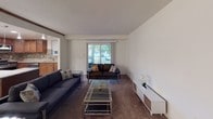 This single-floor residence offers a thoughtfully designed layout that balances comfort and functionality across its main living spaces. The living room is generously proportioned, featuring neutral white walls, carpeted flooring, and a vaulted ceiling detail that adds architectural interest. A large sliding glass door floods the space with natural light and provides outdoor views, while the open sightline to the kitchen enhances the sense of openness throughout.

The kitchen is a standout feature, equipped with rich warm-toned wood cabinetry, granite countertops, and a decorative mosaic tile backsplash. Stainless steel appliances, including a gas range, over-the-range microwave, French door refrigerator, and dishwasher, complete the well-appointed space. Tile flooring adds durability and a clean aesthetic.

The primary bedroom is spacious and carpeted, offering natural light through a window and notable closet space via dual bifold closets. The second bedroom is cozy and equally well-lit with its own window and neutral carpeting. Both bathrooms are finished cleanly, with one featuring a tub-shower combination with mosaic tile accenting, and the other offering a white vanity with a vessel sink and tiled wainscoting.