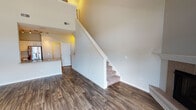 Located at Chamberlain Lane in Naperville, Illinois, this two-story residence offers a well-designed layout that balances open living spaces with functional room separation across both levels. The main floor features a spacious living area distinguished by soaring double-height ceilings and large French doors topped with transom windows, flooding the space with natural light and providing access to an outdoor balcony with neighborhood views. A fireplace anchors one wall of the living area, adding a notable architectural detail. Wood-style plank flooring runs throughout the main level, lending a clean, cohesive aesthetic.

The kitchen is equipped with white cabinetry, granite-style countertops, and a full suite of stainless steel appliances, including a gas range, over-the-range microwave, and refrigerator. A half bathroom is conveniently located on the main floor.

A carpeted staircase leads to the upper level, where the hallway opens to a landing with an open railing overlooking the lower floor. The bedrooms upstairs feature plush carpet, ceiling fans, and windows offering exterior views. Closet storage is available in the upper-level rooms. A full bathroom with a tiled tub-shower combination and wood-style flooring completes the upper level.