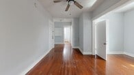 Located at 308 Grove St N in the heart of Saint Petersburg, FL, this unit offers a well-organized single-floor layout comprising a living room, kitchen, bathroom, two hallways, and a closet. The living room is a bright, open space characterized by rich hardwood floors, soft gray walls, and multiple windows fitted with blinds that allow generous natural light to filter in. A ceiling fan with a light fixture is mounted on the textured ceiling, adding both function and a classic touch. The hallways connect the rooms efficiently and continue the warm hardwood flooring throughout. The kitchen features warm-toned wood cabinetry, granite-look countertops, a stainless steel sink, and a white electric range, all set against light hardwood floors and clean gray walls. The bathroom is a standout space, showcasing a charming freestanding clawfoot soaking tub, a white vanity, and a bright window that fills the room with natural light — a nod to the building's classic character. A dedicated closet provides practical storage. Throughout the unit, the consistent use of light gray paint, white trim, and hardwood flooring creates a cohesive and timeless aesthetic well-suited to urban living in downtown Saint Petersburg.