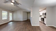 This 1-bedroom, 1-bathroom residence offers a thoughtfully designed layout that maximizes comfort and functionality. The open-concept living, dining, and kitchen area forms the heart of the home, featuring rich dark hardwood-style flooring and vaulted ceilings accented by a ceiling fan that add a sense of spaciousness and airiness. Multiple windows throughout the living area invite generous natural light, enhancing the warm, neutral color palette of the walls and trim.

The galley-style kitchen is well-equipped with crisp white cabinetry, granite-look countertops, and a full suite of stainless steel appliances including a refrigerator, dishwasher, range, and microwave. The dining area is highlighted by a modern pendant light fixture, creating a welcoming atmosphere for meals.

The bedroom is a comfortable retreat, featuring plush carpet flooring and a window with blinds that allows for natural light while maintaining privacy. An attached walk-in closet with wire shelving provides ample storage.

The full bathroom is finished with a granite-topped vanity, white cabinetry, a full tub-shower combination with tile surround, and matching hardwood-style flooring, creating a clean and cohesive aesthetic throughout the home.