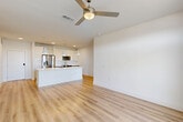 Located in Katy, TX, this well-appointed 2-bedroom, 2-bathroom single-story home offers a thoughtfully designed open-concept layout with modern finishes throughout. Light wood-look flooring flows seamlessly across the living, dining, and kitchen areas, creating a bright and cohesive atmosphere enhanced by crisp white walls and recessed lighting.

The kitchen is a standout feature, showcasing white shaker cabinetry, a large center island with a white quartz countertop, a stainless steel appliance suite, subway tile backsplash, and stylish pendant lighting overhead. The adjacent dining and living areas are bathed in natural light and anchored by a ceiling fan, with French doors opening onto a private balcony that overlooks a scenic pond and landscaped greenway.

The primary bedroom is a comfortable retreat with its own ceiling fan, French door balcony access, and generous closet storage. The bathrooms are finished with wood-look flooring, grey-toned vanities with white countertops, and a tub-shower combination featuring elegant marble-style tile surround. Additional highlights include three closets with built-in shelving, a dedicated laundry area, and a welcoming entrance foyer. The overall ambiance is clean, modern, and move-in ready.