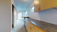 This single-floor unit offers a clean, functional layout designed to maximize natural light and urban views. The main living area is expansive and airy, featuring large windows on multiple walls alongside a sliding glass door that opens to a private balcony overlooking surrounding city buildings. Plush wall-to-wall carpeting runs throughout the living and sleeping areas, contributing to a comfortable, quiet atmosphere.

The galley-style kitchen is efficiently arranged with light maple cabinetry, dark laminate countertops, and a compact peninsula that doubles as a breakfast bar. An under-counter refrigerator provides built-in storage, while upper cabinets and generous counter space offer practical utility. A dedicated electrical panel is conveniently recessed into the wall near the entry.

The bedroom is generously proportioned, featuring soft carpeting, crisp white walls, and ample room for a variety of furniture configurations. Natural light filters in, creating a bright and welcoming space.

The full bathroom is neatly appointed with a single-sink vanity featuring maple cabinetry with brushed hardware, a full-size soaking tub with shower, and tile flooring in a neutral stone pattern. The overall design of the unit is understated and contemporary, with a clean white palette throughout that provides a versatile canvas for personalization.