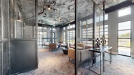 Located at 5 Resort Dr in Savannah, Georgia, this single-floor amenity facility offers a generously sized, thoughtfully designed space that blends industrial aesthetics with modern sophistication. The exposed ceilings reveal ductwork and structural elements finished in dark tones, complemented by pendant lighting that creates a warm, dynamic atmosphere throughout.

The fitness area is extensive and well-appointed, featuring a wide array of strength training equipment including cable machines, power racks, and a full dumbbell rack. A dedicated cardio zone houses multiple treadmills and an elliptical, while a separate studio space is equipped with cycling bikes, a ballet barre, exercise balls, and a mounted flat-screen display — ideal for group classes or individual training sessions. Floor-to-ceiling mirrors amplify the sense of space across the gym floor.

Adjacent to the fitness areas, a contemporary lounge space provides a welcoming retreat. Sleek metal mesh partitions divide the seating zones while maintaining visual openness. Modern low-profile furniture in neutral tones is arranged for social interaction, surrounded by large windows that invite abundant natural light and views of the surrounding landscape. Patterned carpet flooring flows cohesively throughout, tying the industrial and refined design elements together seamlessly.