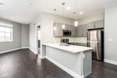 This single-floor residence offers 2 bedrooms and 3 bathrooms within a efficiently designed layout. The open-concept kitchen serves as the centerpiece of the living area, featuring gray shaker-style cabinetry, white quartz countertops, a subway tile backsplash, and a full suite of stainless steel appliances including a range, microwave, and dishwasher. A peninsula with an undermount sink and pendant lighting above creates a natural divide between the kitchen and living area, which benefits from natural light through double-pane windows.

Dark hardwood-style flooring runs throughout the main living and kitchen areas, lending a cohesive, modern aesthetic. The bedrooms are carpeted for comfort, with the primary bedroom featuring its own dedicated access point and a generously sized window. The secondary bedroom also includes natural light and connects to adjoining spaces seamlessly.

The three bathrooms are finished with gray vanity cabinetry, white quartz countertops, and marble-style tile surrounds. One bathroom features a glass-enclosed shower, while another includes a soaking tub. The overall palette of soft grays and whites throughout creates a clean, contemporary ambiance.