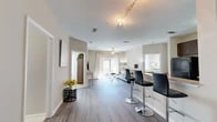 This single-floor residence offers a thoughtfully designed layout accommodating three bedrooms and two full bathrooms. The open-concept living and dining area is finished with durable wood-look plank flooring and neutral warm-gray walls, creating a bright, cohesive atmosphere. Track lighting and a ceiling fan complement the space, while a sliding glass door floods the living room with natural light and provides direct access to a private outdoor patio with exterior views.

The galley-style kitchen features dark espresso cabinetry with brushed nickel hardware, speckled countertops, stainless steel appliances, and light ceramic tile flooring, offering efficient use of the available space.

The primary bedroom is generously proportioned with large windows that invite ample natural light and is accompanied by an en-suite bathroom featuring a soaking tub, tile flooring, a wide vanity with undermount sink, and speckled countertops matching the kitchen. Additional bedrooms are carpeted and well-lit with large windows. A walk-in closet with wire shelving provides organized storage. The overall ambiance is clean, modern, and move-in ready.