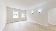 Located at 702 S Mariposa Ave in the heart of Los Angeles' Koreatown neighborhood, this two-bedroom, one-bathroom unit offers a thoughtfully laid-out single-floor plan with a clean, modern aesthetic. Light-toned hardwood flooring runs throughout, complementing the warm neutral walls and white trim that give the space a bright, cohesive feel.

The living and dining areas provide comfortable gathering spaces, while two connecting hallways ensure easy flow between rooms. The kitchen is a standout feature, showcasing beadboard-style grey cabinetry, white countertops, a matte black faucet with an undermount stainless steel sink, and herringbone-pattern tile flooring — all bathed in natural light from an adjacent window.

Both bedrooms are well-proportioned, with the primary bedroom offering generous space. Each room features large, multi-pane windows that invite abundant natural light and offer views of the surrounding Los Angeles cityscape and neighborhood. Elegant wall sconces provide warm accent lighting throughout.

The bathroom impresses with floor-to-ceiling marble-effect tile in the walk-in shower, fitted with a sleek glass door and a dark bronze grab bar, adding a refined, upscale touch. The overall design is clean, minimal, and move-in ready, making this a well-appointed urban residence.