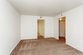 This single-floor unit offers a practical and straightforward layout, as illustrated by the 3D floor plan, which reveals a well-organized arrangement of living spaces. The kitchen is equipped with warm honey-toned wood cabinetry providing ample upper and lower storage, light-colored countertops, a double sink, and white appliances including an electric range and a full-size refrigerator. The kitchen benefits significantly from a sliding glass door that floods the space with natural light and offers a direct view of a lush, green outdoor area. The tile flooring in the kitchen provides a clean, durable surface.

The bedrooms are carpeted in a warm mauve-toned carpet and feature neutral white walls. Multiple windows fitted with horizontal blinds allow natural light to enter each room. The living area is also carpeted and opens through doorways into the adjacent bedrooms and hallway, creating a connected and functional flow throughout the unit.

The bathroom includes a wood-vanity with a white countertop, tile flooring, a built-in linen closet with open shelving, and a full tub and shower combination with white ceramic tile surround and chrome fixtures. The overall aesthetic of the unit is clean and neutral throughout.