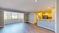 Located at 11709 S Laurel Dr in Laurel, MD, this well-appointed one-bedroom, one-bathroom unit offers a thoughtfully designed single-floor layout. The open-concept living area is bright and welcoming, featuring durable hardwood-style flooring and a large bank of windows fitted with vertical blinds that usher in generous natural light and outdoor views. The kitchen is a standout feature, showcasing crisp white shaker-style cabinetry, marble-look countertops, a breakfast bar peninsula, and a full suite of stainless steel appliances including a refrigerator, range, and microwave. Recessed lighting enhances the kitchen's clean, modern aesthetic. The spacious bedroom is finished with plush wall-to-wall carpeting, a ceiling fan with light fixture, a window for natural light, and two closets offering ample storage. The full bathroom is neatly appointed with a tub/shower combination, brushed gold fixtures, a marble-look vanity countertop, and matching hardwood-style flooring. A hallway connects the living spaces efficiently, and neutral gray tones throughout create a cohesive, move-in-ready atmosphere. The unit also includes a dedicated entry hallway, adding a practical transition space.